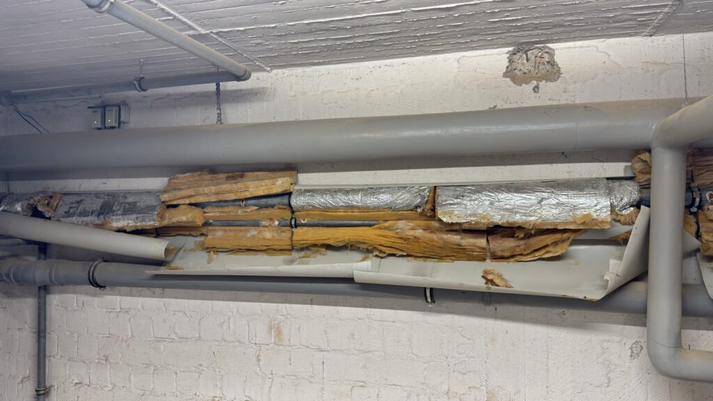 Beschädigte Rohrdämmung und eine Betonabplatzung an der Decke im Technikbereich