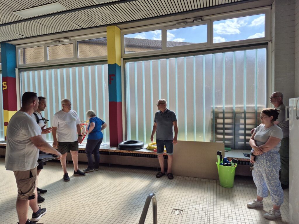 Teilnehmende des Ortstermins – Gemeindeverwaltung, Verein, Hausmeister, Ratsmitglied und Ortsvorsteher – in der stillgelegten Schwimmhalle der Lerchenschule Faßberg