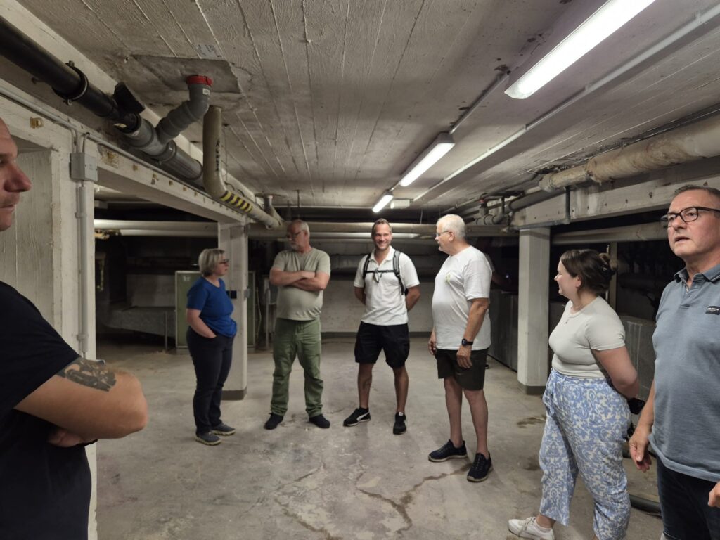 Teilnehmende des Ortstermins – Gemeindeverwaltung, Verein, Hausmeister, Ratsmitglied und Ortsvorsteher – im Technikkeller des Lehrschwimmbeckens Faßberg